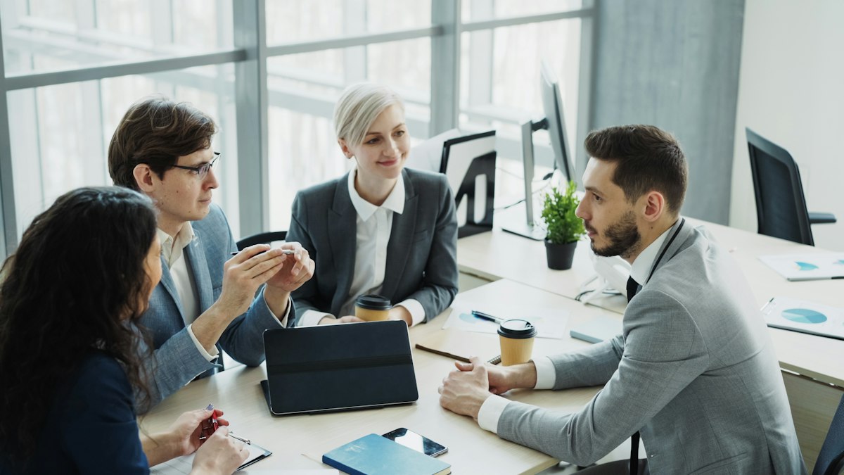 Consultanți discutând planul de contabilitate și implementare cu un client, la o masă de birou